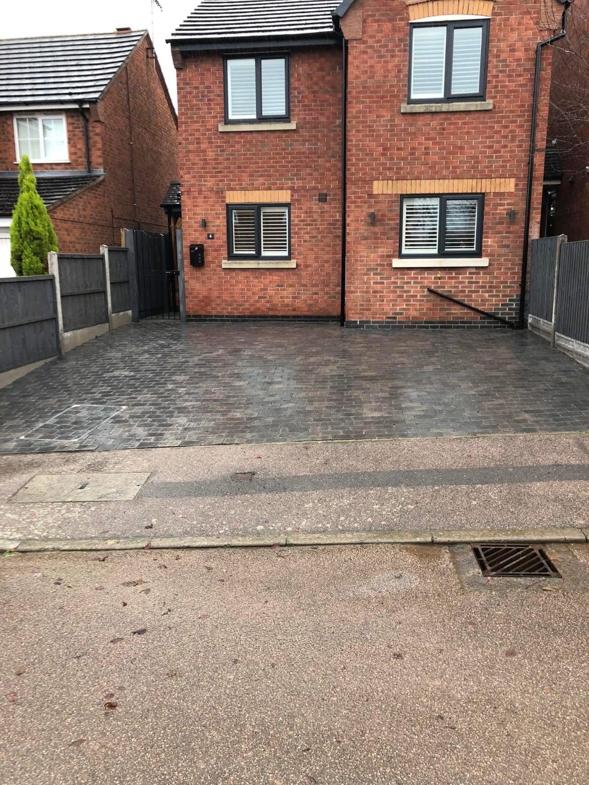 Finished grey block-paved driveway in front of a red brick detached house